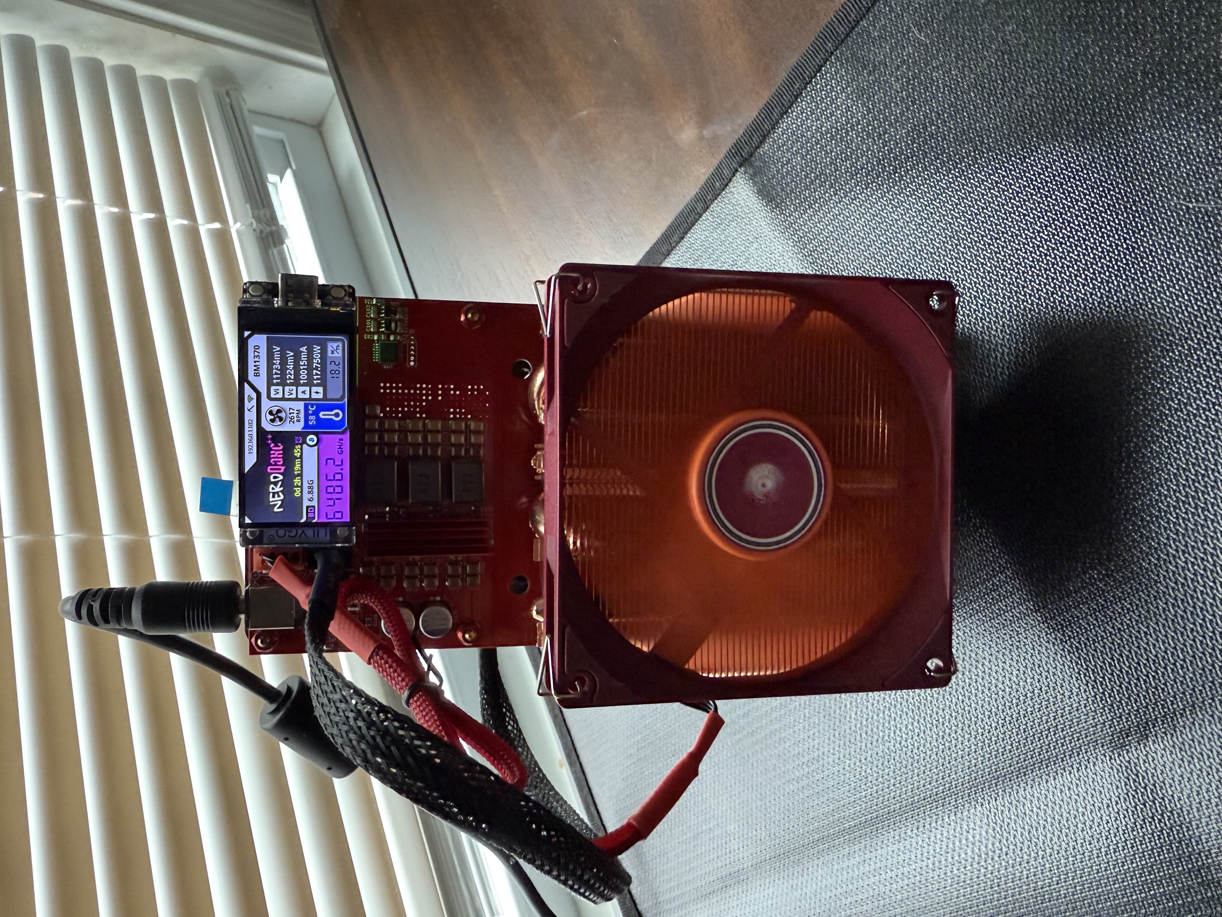 Close-up of NerdQaxe++ LCD showing around 6.48 TH/s with temps and voltage.